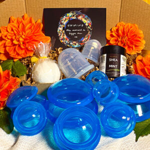 blue silicone cups, bath bomb, cbd salve and postcard in gift box surrounded by orange dahlias