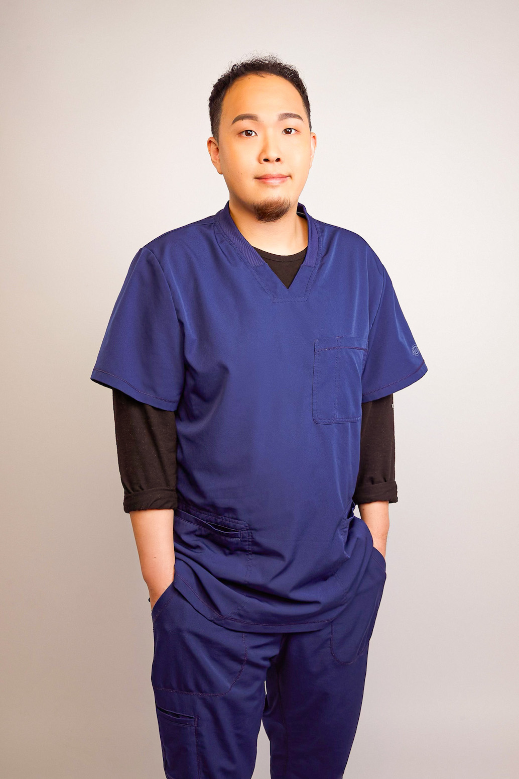 Acupuncturist standing facing camera in blue scrubs.